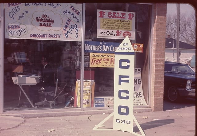 A CFCO on-remote sign in a shop window plastered with sale banners