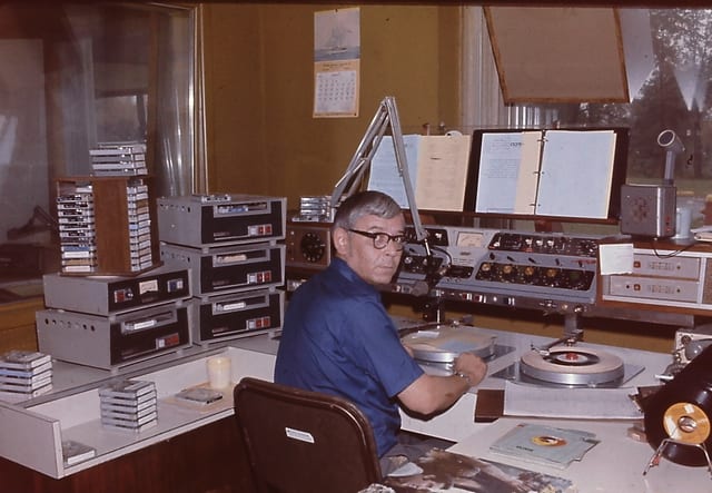 An operator cues a record at the master control desk stacked with carts
