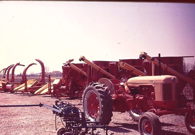 Case tractors and augers lined up on the dealer lot