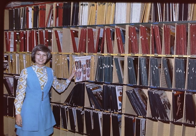 A staffer picks a record from the packed library shelves
