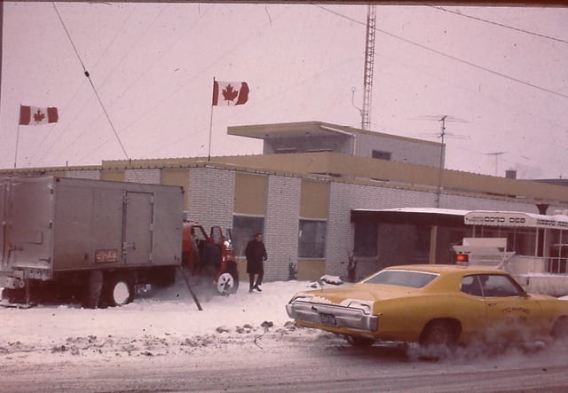 A yellow car passes the snowy studio lot